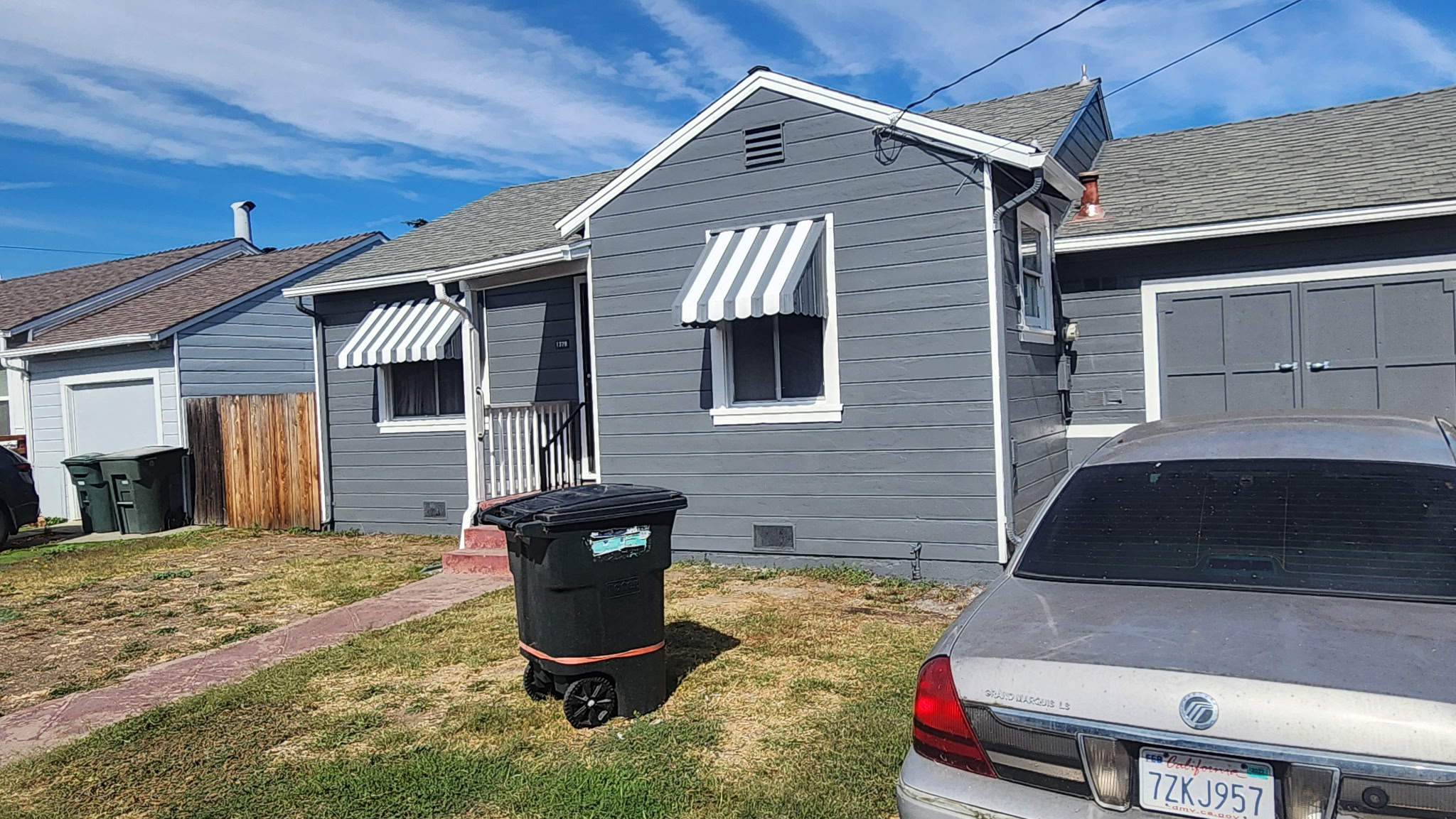 Completed residential exterior painting project with gray siding and white trim